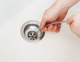 Blocked drain being cleared with plumbing tools